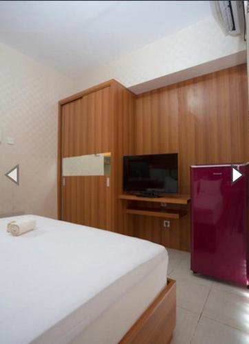 a bedroom with a bed and a flat screen tv at Apartemen Taman Melati Margonda by Winroom in Kukusan