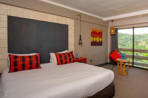 - une chambre dotée d'un grand lit avec des oreillers rouges et noirs dans l'établissement 26° South Bush Boho Hotel, à Muldersdrift