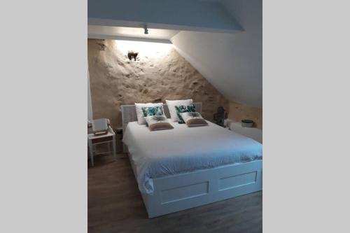 1 dormitorio con cama y pared de piedra en TY FAROMA, en Sarzeau