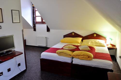 sypialnia z łóżkiem z żółtymi poduszkami i telewizorem w obiekcie Hotel St Florian w mieście Loket