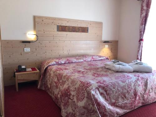 a bedroom with a large bed with a wooden headboard at Hotel Paradiso in Asiago