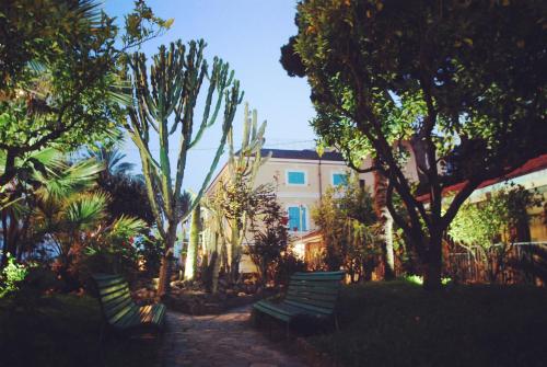 two green benches in front of a building with trees at Hotel Villa Sophia in Sanremo