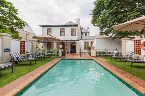 a swimming pool in the yard of a house with chairs at Courtyard Hotel Arcadia in Pretoria