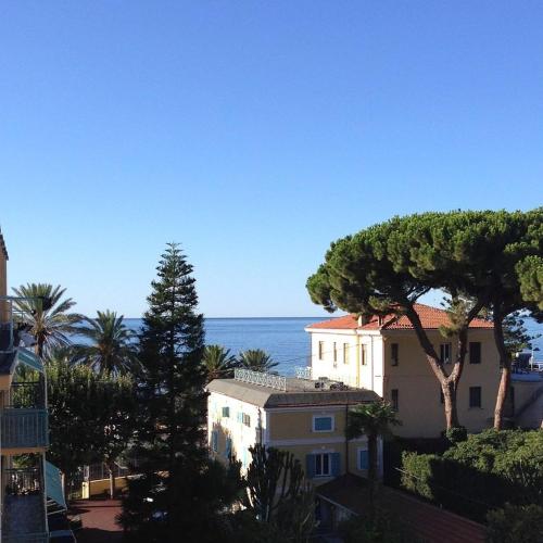 a building with trees and the ocean in the background at Hotel Villa Sophia in Sanremo