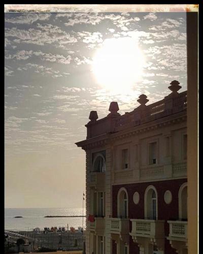 a building on the beach with the sun behind it at Grand Hotel Cesenatico in Cesenatico