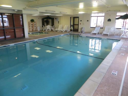 a swimming pool with blue water and white chairs at Wingate by Wyndham in Peoria