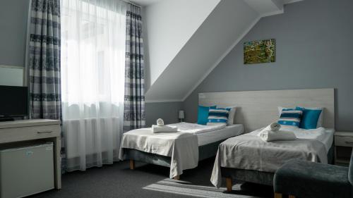 a hotel room with two beds and a television at Ośrodek LZS CIS "Od Nowa" in Mielno