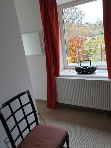 a room with a chair and a window with a radio at VILLA GABRIEL in Trois-Ponts