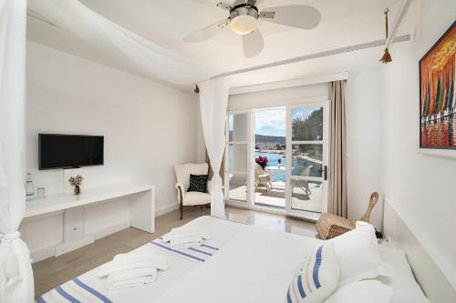 a bedroom with a bed and a desk and a television at Port Alacati Hotel in Alacati