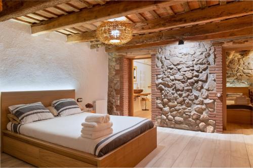 a bedroom with a bed and a stone wall at Masovería l'Era in Arbúcies