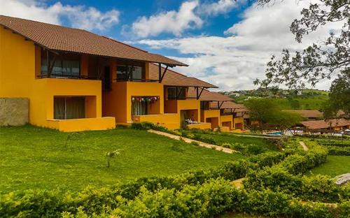 ein gelbes Haus mit einem grünen Hof davor in der Unterkunft Winterville Gravatá in Gravatá