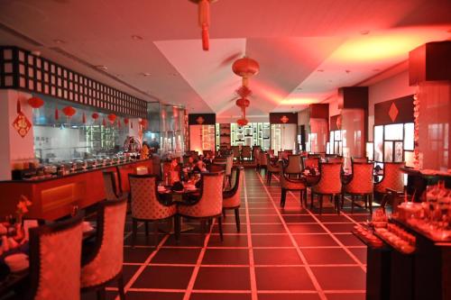 a restaurant with red chairs and a bar at Pearl Continental Hotel, Karachi in Karachi