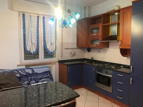 cocina con armarios azules y encimera negra en Appartamento Fano zona lido, en Fano