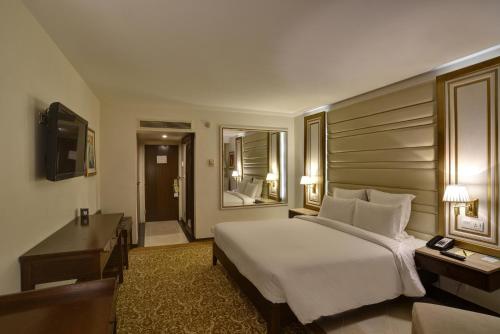 a bedroom with a bed and a desk and a television at Pearl Continental Hotel, Karachi in Karachi