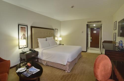 um quarto de hotel com uma cama grande e uma cadeira em Pearl Continental Hotel, Karachi em Karachi