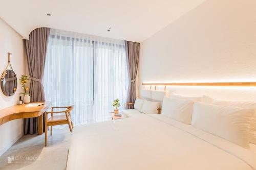 a hotel room with a large white bed and a desk at CityHouse - CityOasis in Ho Chi Minh City