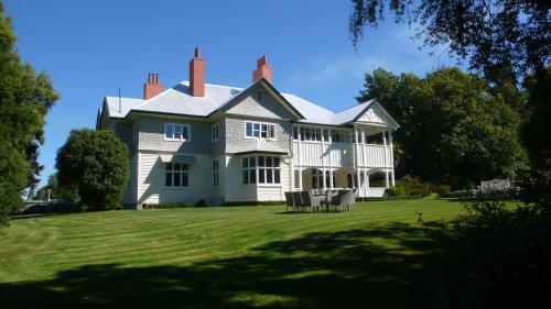 uma grande casa branca num relvado verde em Gunyah Country Estate em Windwhistle