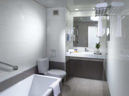 a bathroom with a tub and a toilet and a sink at Lev yerushalayim - suites hotel in Jerusalem