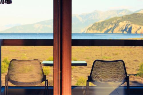 two chairs sitting on a porch with a view of the ocean at Thalatta Seaside Hotel in Ayia anna
