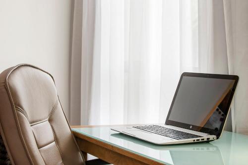 a laptop computer sitting on a glass desk with a chair at Mid City Motel Warrnambool in Warrnambool