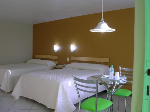 um quarto com duas camas e uma mesa com cadeiras em Hotel San Bernardino em Guaramirim