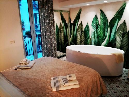 La salle de bains est pourvue d'un lit, d'une baignoire et de plantes. dans l'établissement Sonnino Suite jacuzzi apartment, à Bari