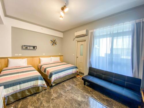 台東市的住宿－15電梯民宿，一间卧室配有两张床和蓝色的沙发