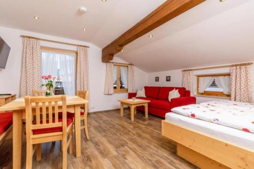 a bedroom with a bed and a red couch at Feichtenhof in Reit im Winkl