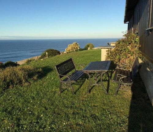 una mesa de picnic y un banco en una colina con vistas al océano en Bungalow 3 (adosado) - Playa Arnela, en Carballo