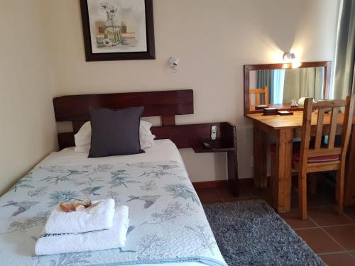 a bedroom with a bed with towels and a desk at Ngwenya Boutique Hotel in Lephalale