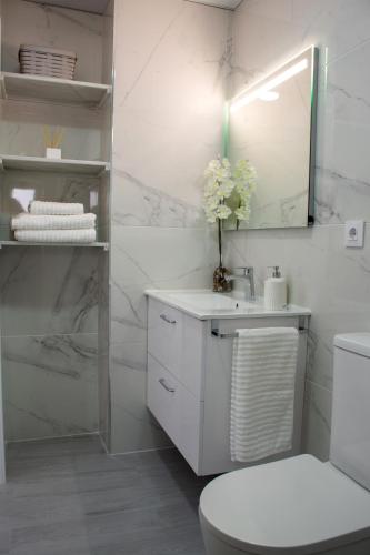 a white bathroom with a toilet and a sink at Apartamento Calma in Vejer de la Frontera