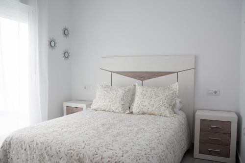a bedroom with a bed with a white bedspread and pillows at Apartamento Calma in Vejer de la Frontera