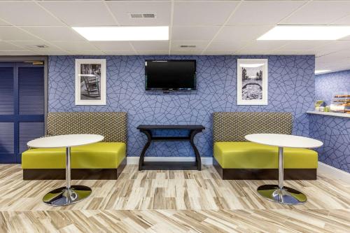 アペックスにあるQuality Inn & Suites Apex-Holly Springsのテーブル2台とテレビ付きの待合室
