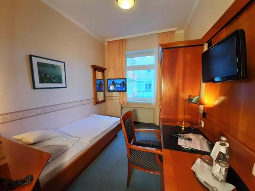 ein Hotelzimmer mit einem Bett, einem Schreibtisch und einem TV in der Unterkunft Hotel Krupp in Bad Neuenahr-Ahrweiler