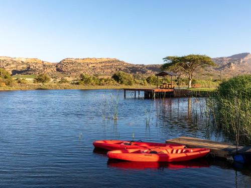 two red canoes sitting on the water next to a dock at Alpha Excelsior Guest Farm in Cederberg