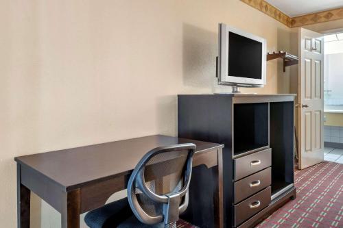 a desk with a chair and a tv on top at Rodeway Inn in New Port Richey