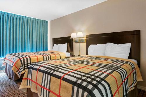 two beds in a hotel room with blue curtains at Rodeway Inn in New Port Richey