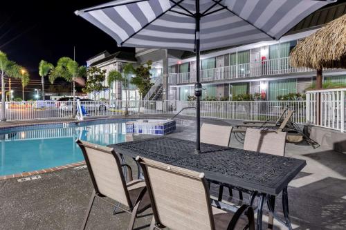 a table with an umbrella next to a swimming pool at Rodeway Inn in New Port Richey