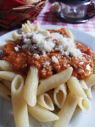 a plate of pasta with meat sauce and cheese at Guesthouse Arnika in Fužine