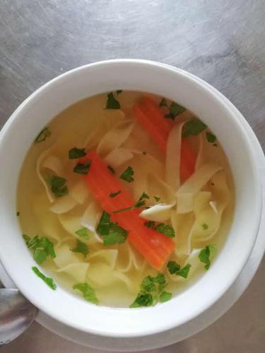 a white bowl of soup with carrots and onions at Guesthouse Arnika in Fužine