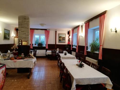 ein Restaurant mit 2 Tischen und weißem Tischtuch in der Unterkunft Guesthouse Arnika in Fužine