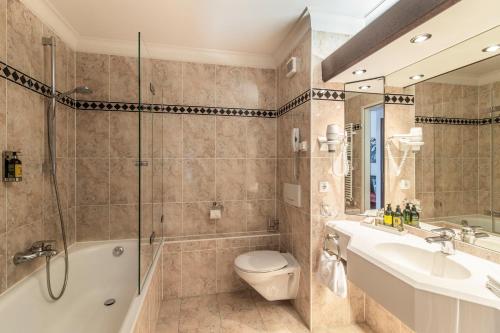 a bathroom with a tub and a toilet and a sink at Alpenhof Murnau in Murnau am Staffelsee