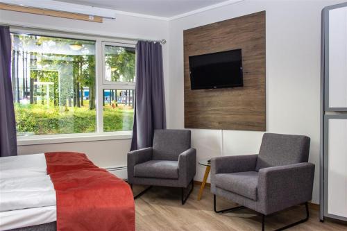 una camera con due sedie, un letto e una TV di Hotell Fritidsparken a Skien