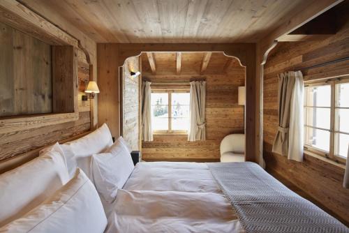 um quarto com uma cama branca num quarto com paredes de madeira em Berghuus Radons em Savognin