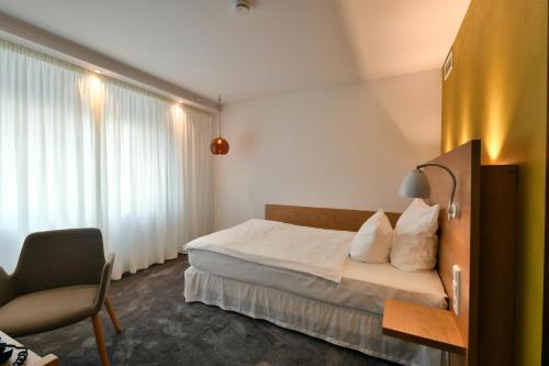 a bedroom with a bed and a chair and a window at Hotel Adler Asperg in Asperg