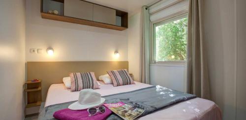 a bedroom with a bed with a hat on it at Mobile Homes by KelAir at Camping La Sirene in Argelès-sur-Mer
