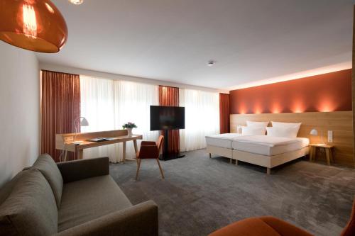 アスペルクにあるHotel Adler Aspergのベッドとソファ付きのホテルルーム
