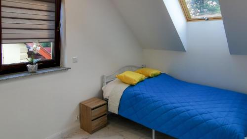 a small bedroom with a blue bed and a window at Luksusowe domy na Mazurach nad jeziorem 2 in Kruklanki