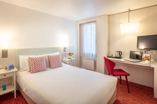 a bedroom with a bed and a desk with a computer at Kyriad Toulouse Blagnac Aéroport in Blagnac