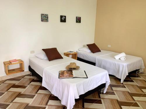 a room with two beds and a book on the table at Hotel La Casablanca Tayrona in Calabazo